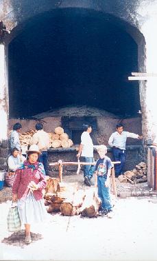 Poor Altiplano people and tourists at a large bread and 